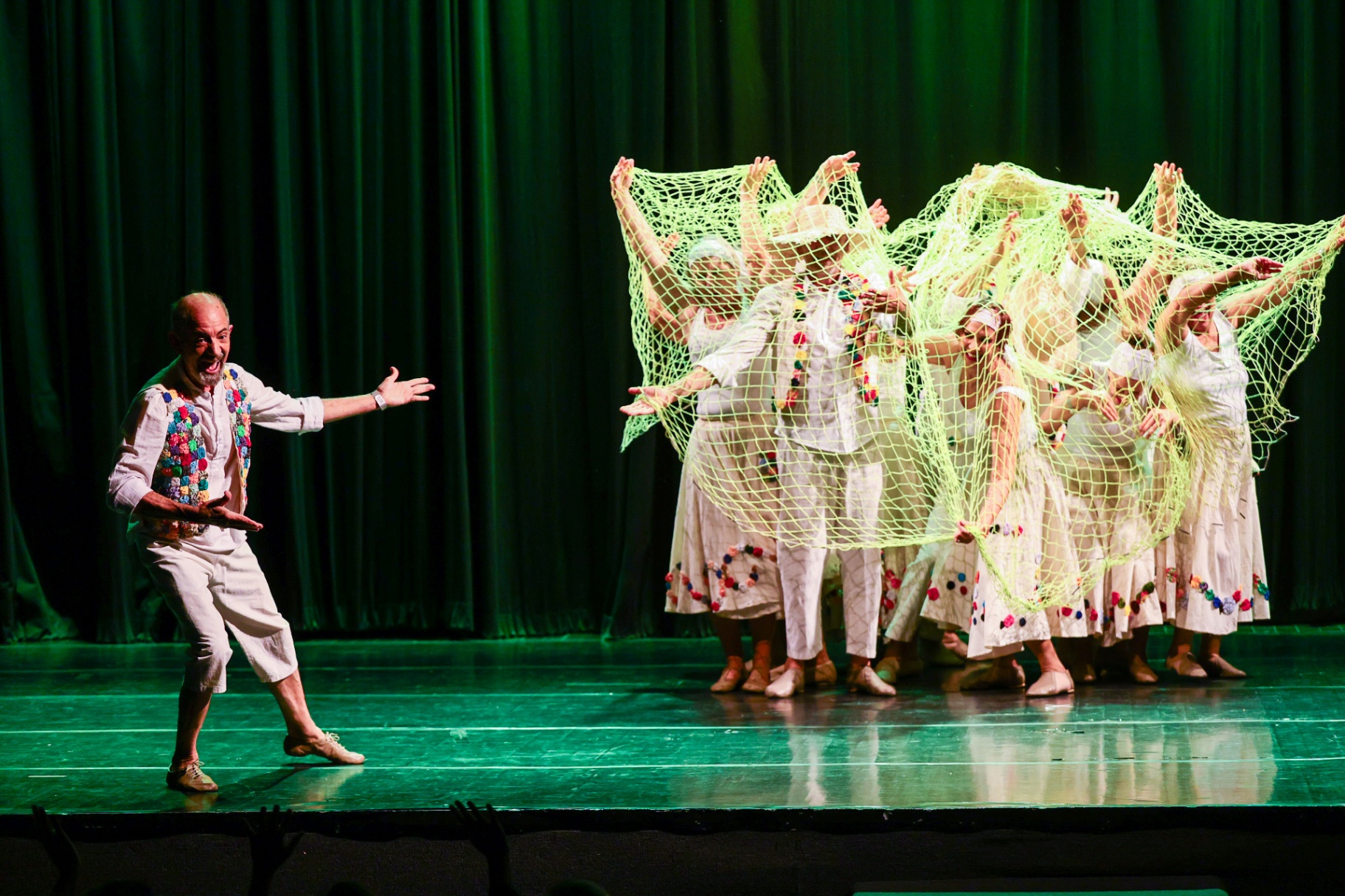 Bailarinos em cena coreográfica com rede verde no palco do FNDC